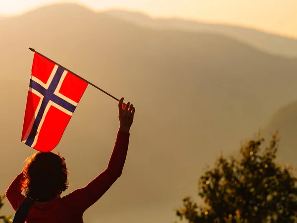Tourist with norwegian flag and mountains landscape
