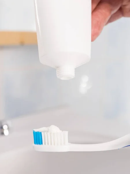 Person putting toothpaste on toothbrush — Stock Photo, Image