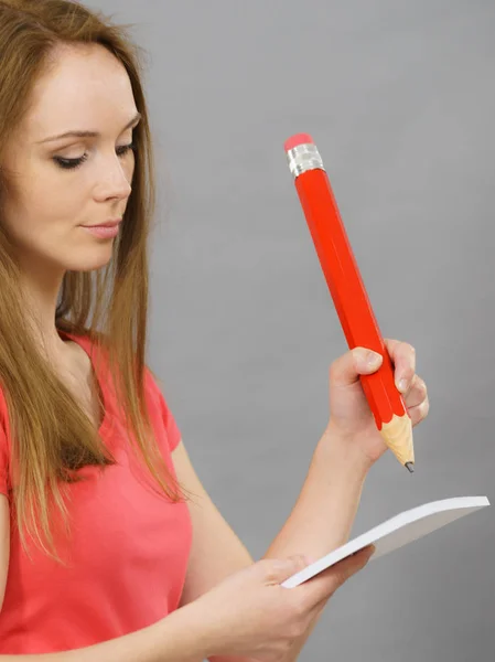 Mujer sostiene enorme lápiz rojo y papel de nota . — Foto de Stock