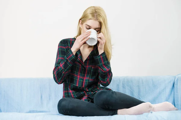 Teenage woman sitting on sofa with mug — Stock Photo, Image