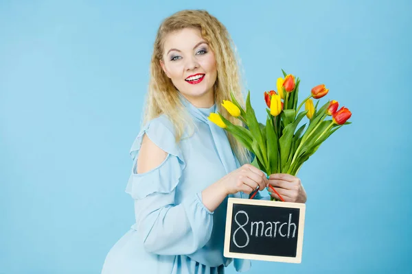 Mujer sostiene tulipanes, tablero con texto 8 marzo —  Fotos de Stock