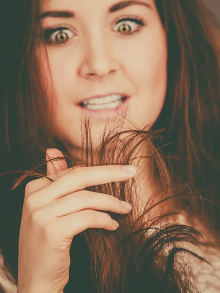 Mujer preocupada mirando sus puntas de cabello seco — Foto de Stock