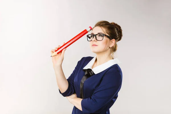 Mujer sosteniendo un gran lápiz de gran tamaño pensando en algo — Foto de Stock