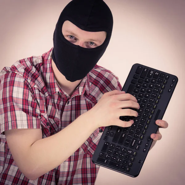 Man dragen balaclava bedrijf toetsenbord — Stockfoto