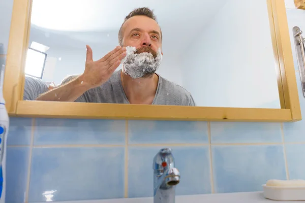 Guy shaving his beard in bathroom — Stock Photo, Image