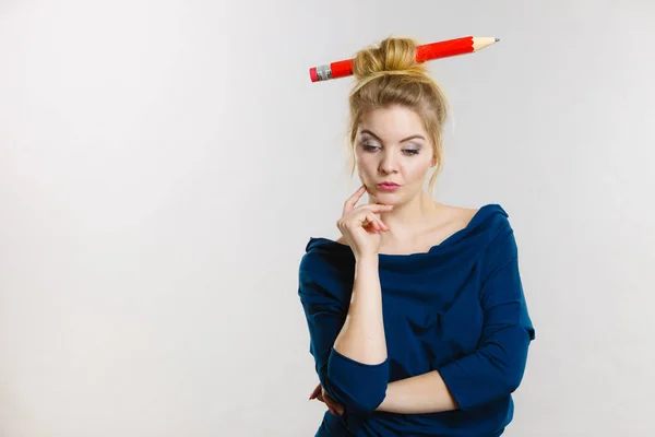 Thinking blonde woman having big pencil in hair — Stock Photo, Image
