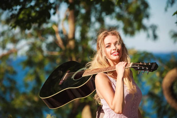 Blonde Frau mit Akustikgitarre am Meer — Stockfoto