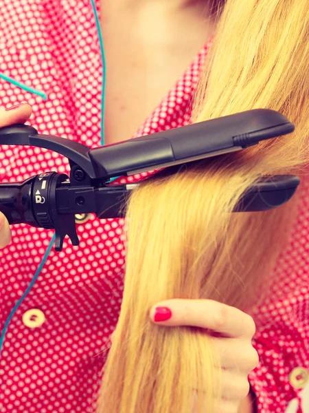 Woman wearing pajamas curling her hair — Stock Photo, Image