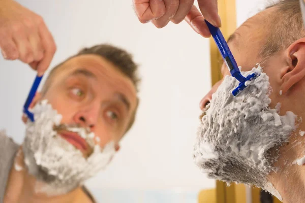 Guy shaving his beard in bathroom — Stock Photo, Image