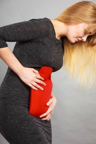 Fille ayant mal au ventre, tenant une bouteille d'eau chaude — Photo