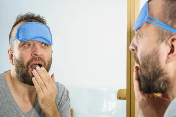 Uomo assonnato che guarda lo specchio e sbadiglia — Foto Stock