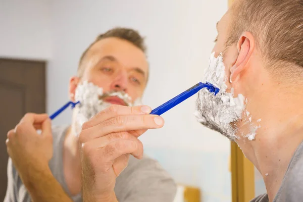 Парень бреет бороду в ванной — стоковое фото