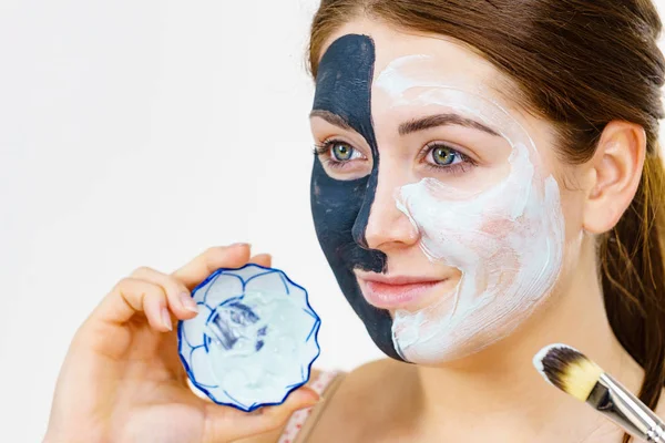 Mädchen schwarze Maske auf halbem Gesicht weißen Schlamm auftragen — Stockfoto