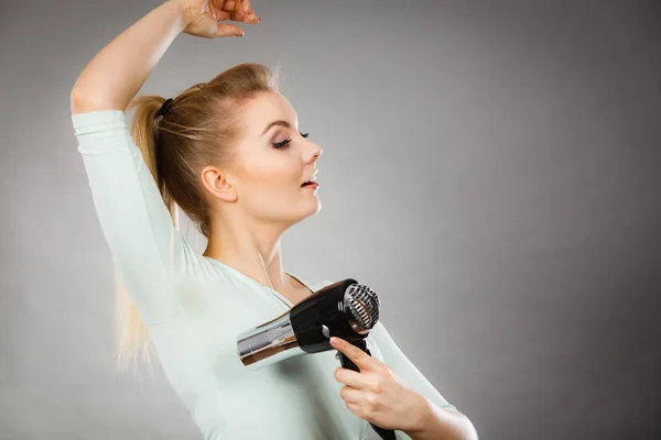 Woman drying armpit with hair dryer — Stock Photo, Image