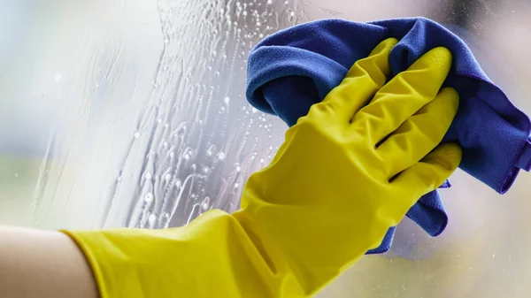 Behandschuhte hände putzen fenstertuch und spray — Stockfoto