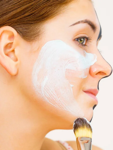 Meisje zwart masker op halve gezicht apply witte modder — Stockfoto