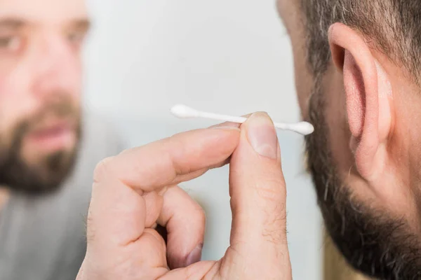 Hombre quitando cera de la oreja usando Q-tip — Foto de Stock