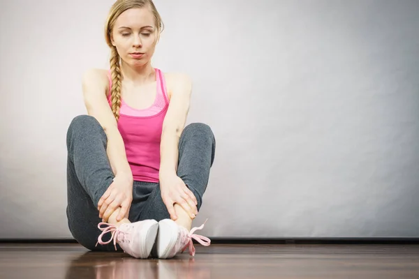 Vrouw in sportkleding zittend op grond — Stockfoto