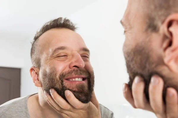 Мужчина смотрит на бороду в зеркало — стоковое фото