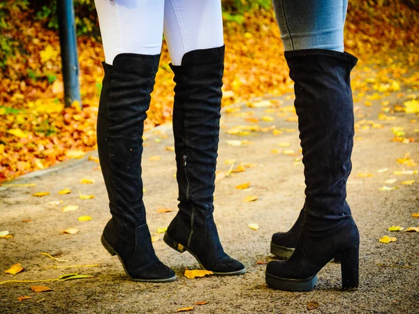 Two women wearing black knee high boots