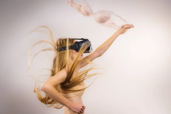 Menina em óculos de realidade virtual detém sutiã — Fotografia de Stock