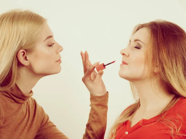 Woman applying her friend lipstick on lips — Stock Photo, Image