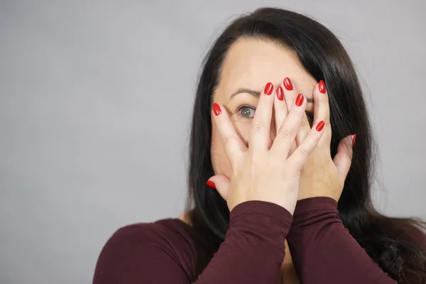 Mulher espreitando através de suas mãos — Fotografia de Stock