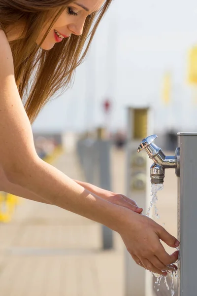 Mujer bebiendo agua del grifo en marina . — Foto de Stock