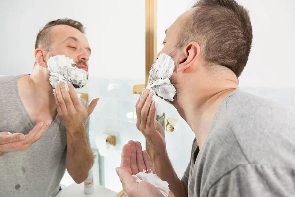 Man applying shaving cream on beard