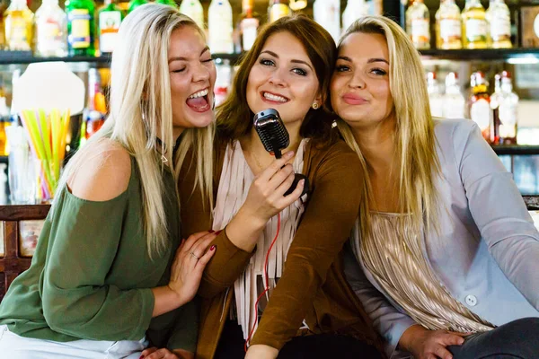 Women in bar singing karaoke