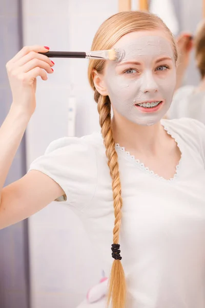 Vrouw met borstel klei modder masker toepassen op haar gezicht — Stockfoto