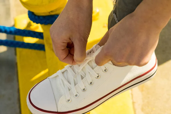 Frau bindet Schuhe, weiße Turnschuhe — Stockfoto