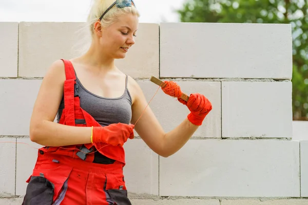 壁の建設のレベルとして文字列を使用して女性のビルダー レンガ屋 進行中の新しい家 — ストック写真