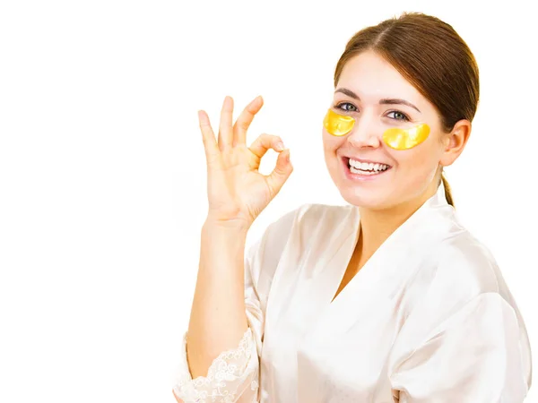 目の下に黄金のコラーゲンパッチを適用する幸せな女性 暗い円を削除マスク 目の周りに繊細な肌の世話をする女の子 美容トリートメント — ストック写真