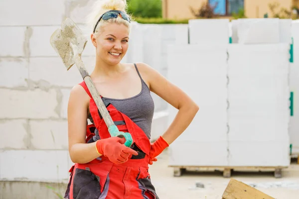 快乐女工用铲子站在工业建筑工地上 努力工作 — 图库照片