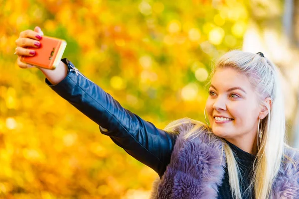 금발의 매력적 여성이 공원에서 유행하는 코트를 스마트폰으로 사진을 즐거운 긍정적 — 스톡 사진