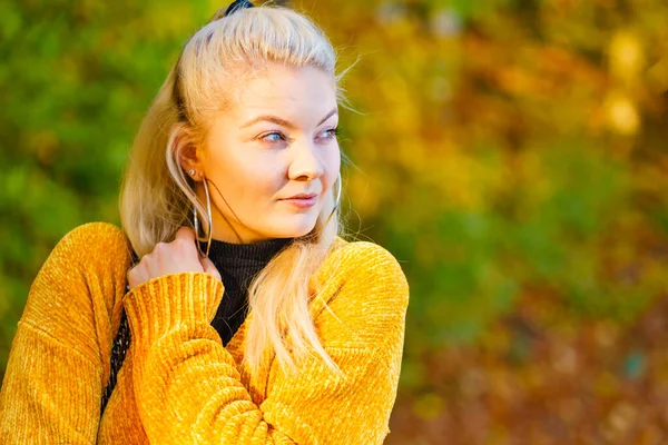 穿着时髦衣服的女人穿着黄色羊毛衫在秋天的公园里散步 — 图库照片