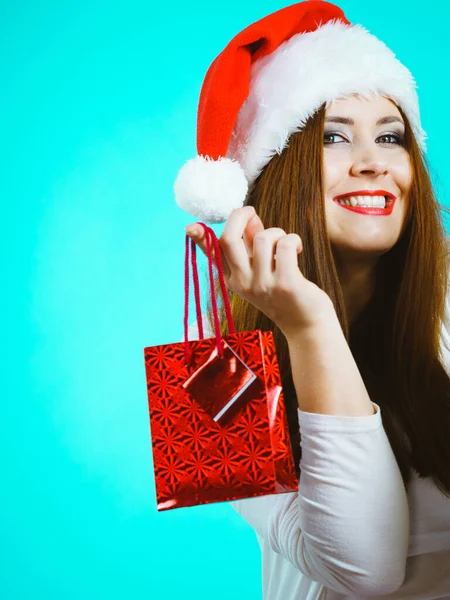 年轻漂亮的成年女子乐于送圣诞礼物 身穿红色圣诞老人帽的女性拿着礼物 蓝色背景 — 图库照片
