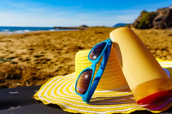 海岸沿いの太陽の保護アクセサリー 砂浜の青いサングラス 黄色の藁帽子と日焼け止めローション 夏休み — ストック写真