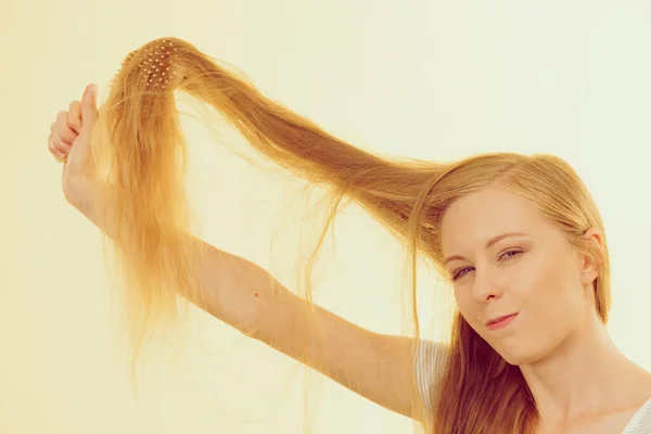 金发女人用刷子梳理她那长长的乱蓬蓬的头发 头发保养得不好的少女 — 图库照片