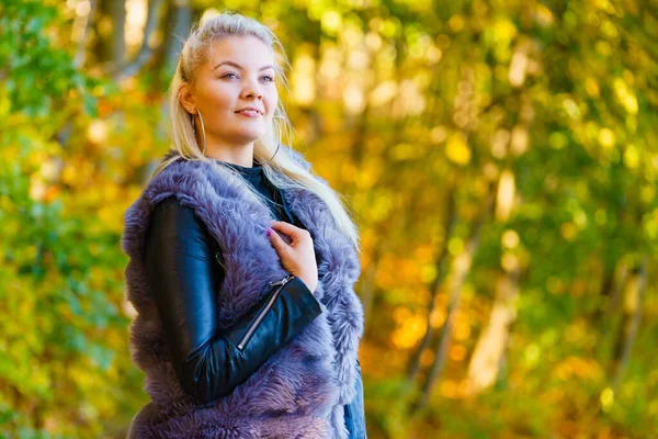 穿着时髦服装的女人在秋天的公园里散步时穿着人造毛皮外套 — 图库照片