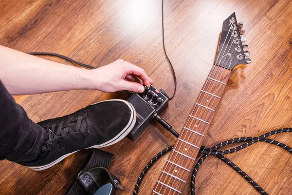 Man with musical instrument setting up guitar audio stomp box effects and cables in music studio