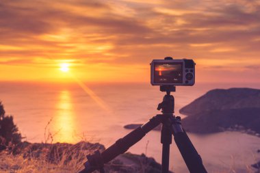 Professional camera taking picture film video of sunrise over sea surface, Greece Peloponnese Mani Peninsula. clipart