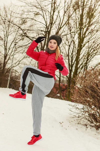 Mujer con ropa deportiva ejercitándose al aire libre durante el