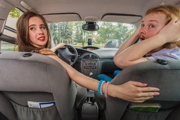 車の中でカップルの友人 車を駐車しようとするハンドルの後ろの女性 乗客の男は怖がってショックを受けて — ストック写真