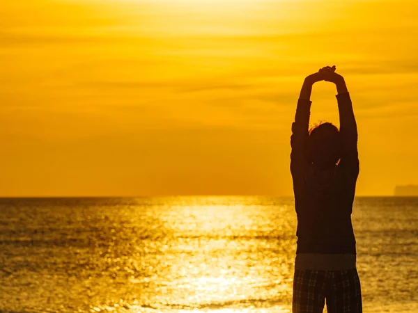 ビーチで夜明けの朝に女性は 海の地平線を見て 腕を上げて日の出を楽しむ バックビュー — ストック写真