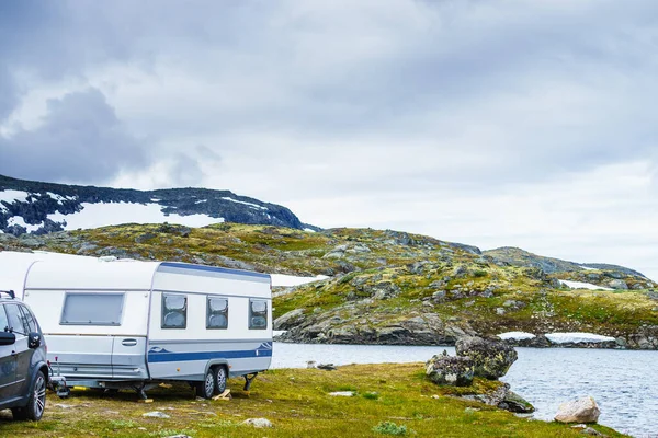 Camper trailer camping on lake in mountains landscape. Norwegian national tourist scenic route Sognefjellet.