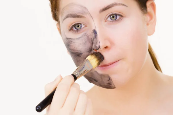 女人在脸上涂粘土碳化硅解毒面罩 用刷子饰物 美容美发吓吓 — 图库照片