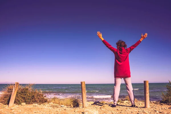 腕を上げて海の景色を楽しむ観光大人の女性は ビーチを歩いてください スペインのコスタ ブランカ — ストック写真