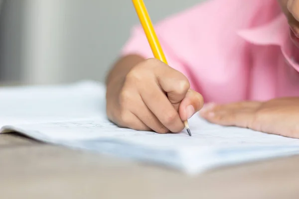 Acercar Una Niña Haciendo Tarea Mano Sostiene Lápiz Amarillo Escribe — Foto de Stock